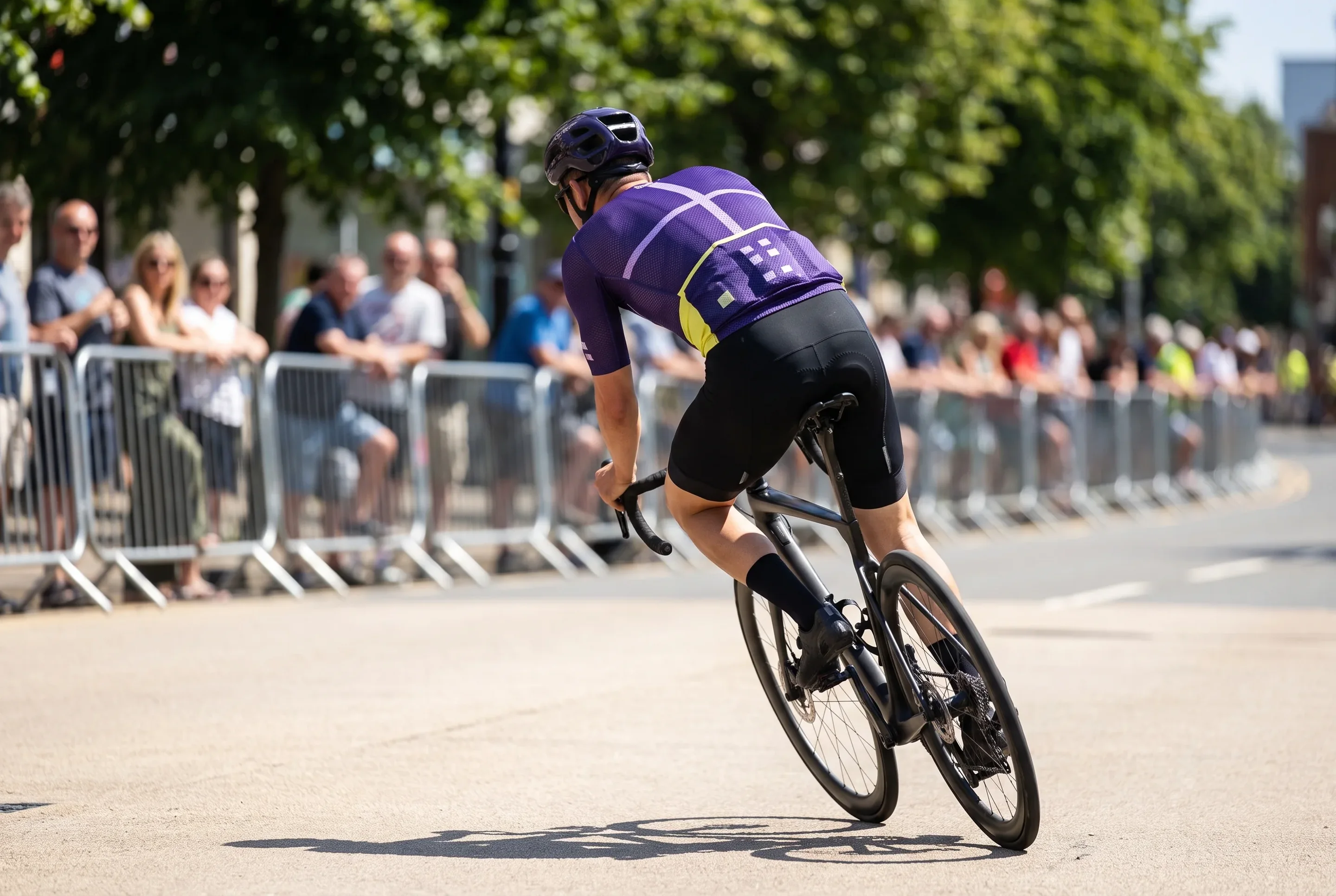 A road racer seen from behind in a summer criterium, the mesh back, side panels and sleeves of the jersey facing the camera