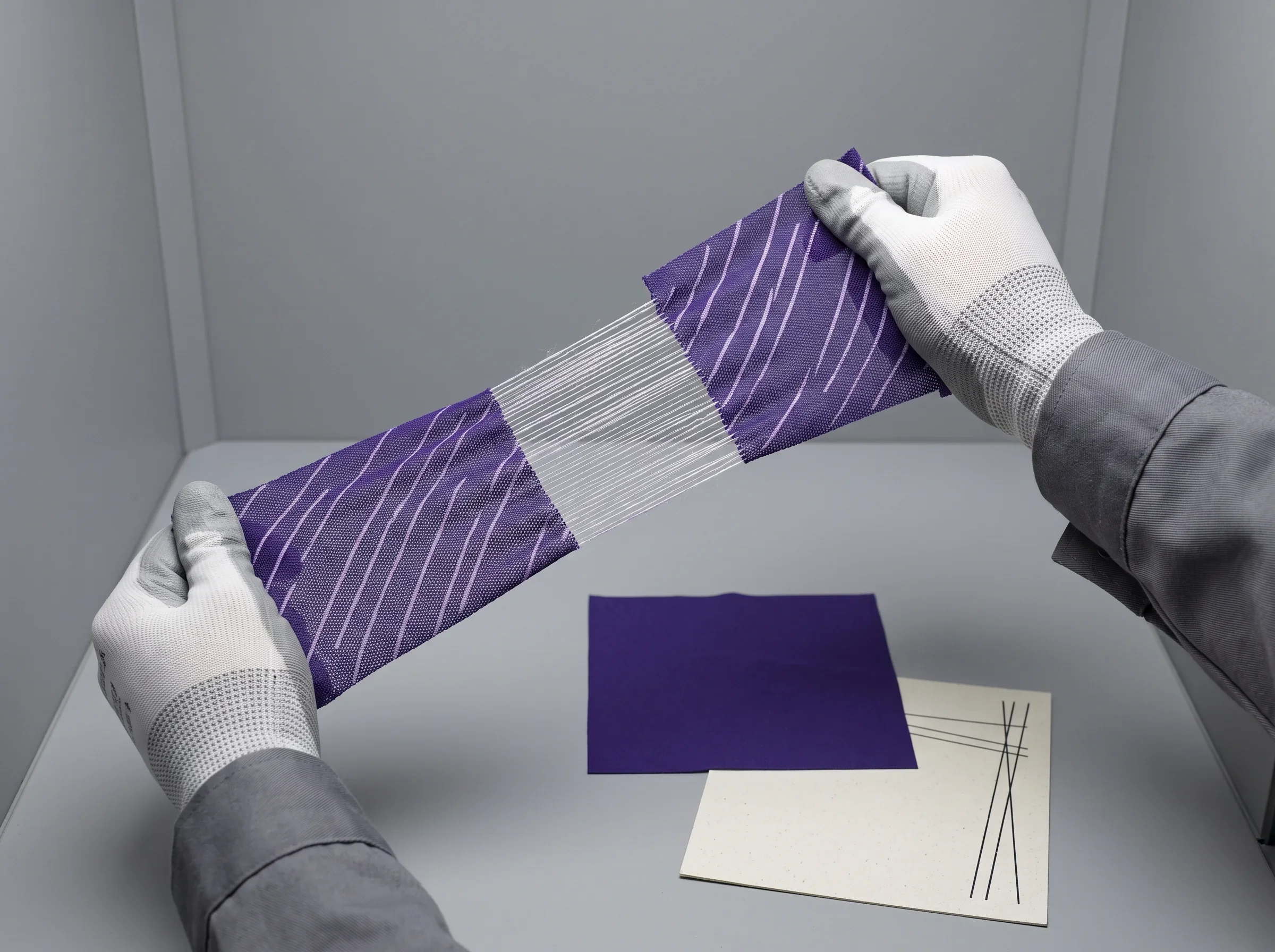 A colour and print technician stretching a printed mesh strike-off by hand under D65 light